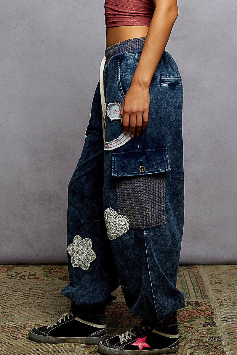 Person wearing blue jeans with patches on a gray background