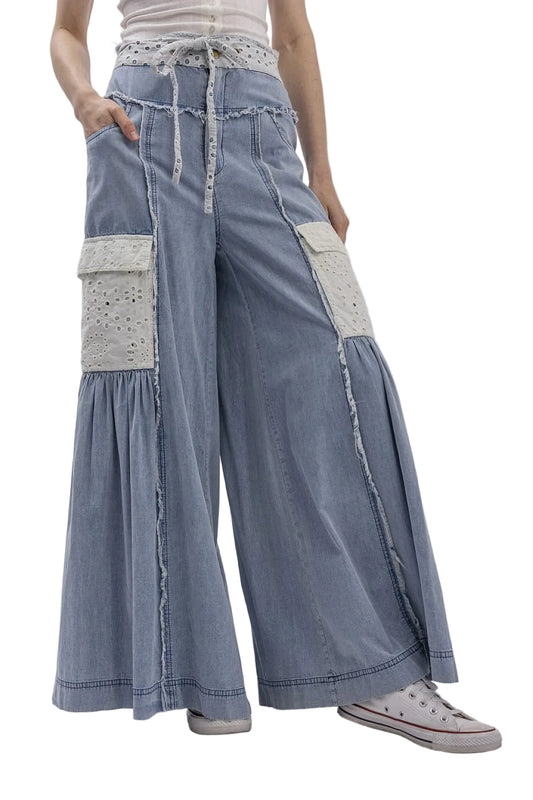 Person wearing blue denim pants with white lace details on a plain background