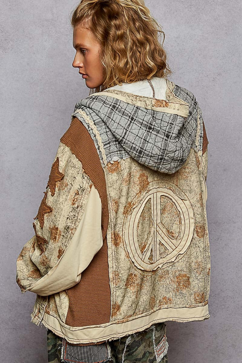 Person wearing a patterned jacket with a peace symbol on a plain background