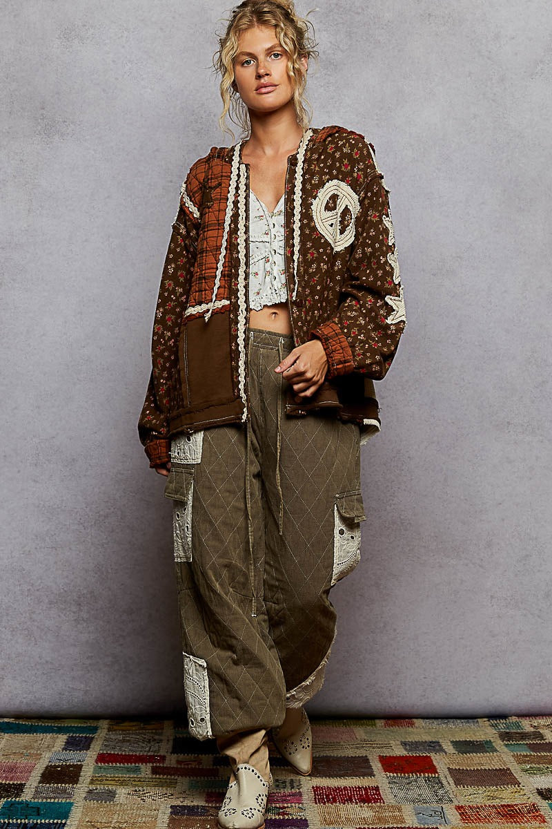 Woman wearing a patterned jacket and baggy pants against a plain background