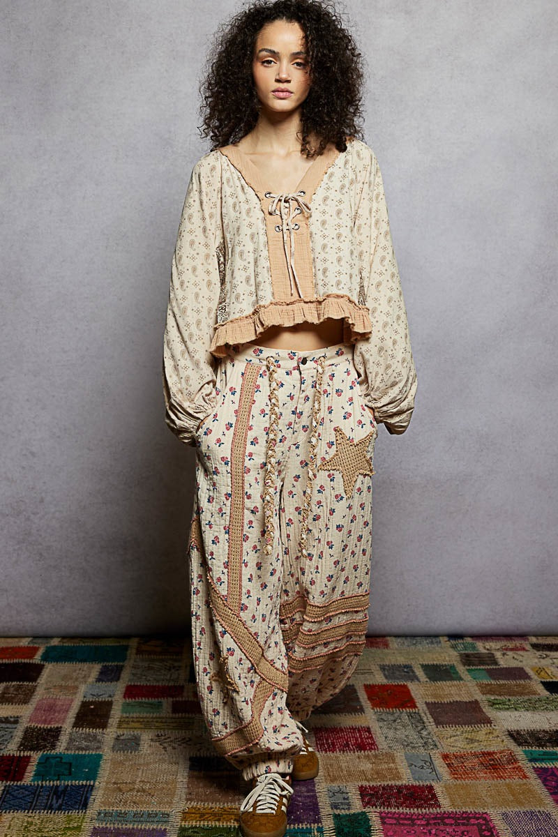 Woman wearing a patterned outfit standing on a colorful rug with a gray wall background