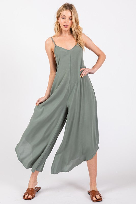 a woman wearing a green jumpsuit and sandals