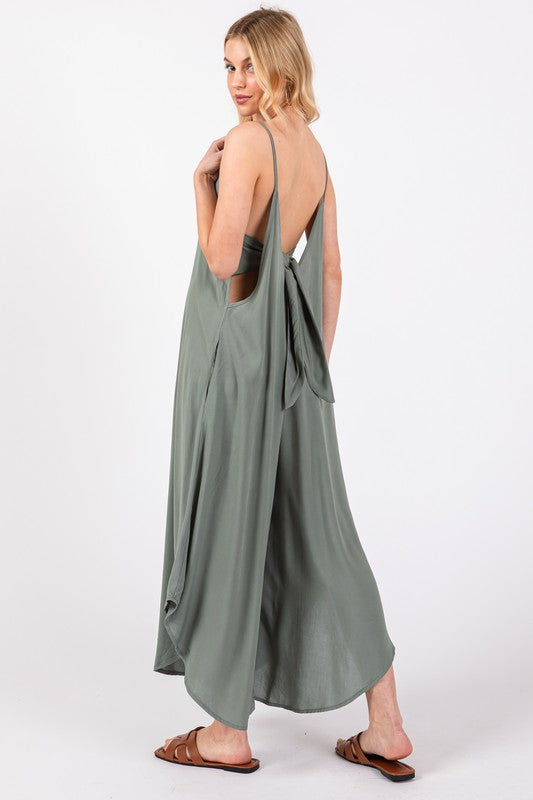 a woman in a green dress is standing with her back to the camera