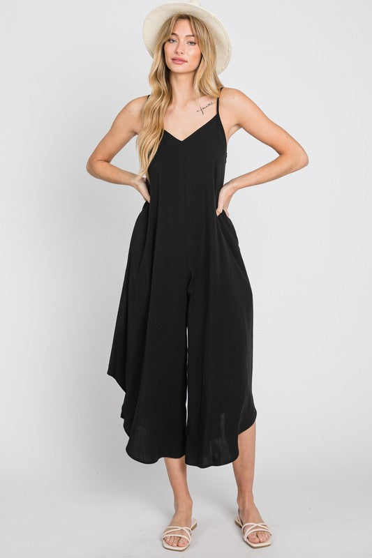 a woman wearing a black jumpsuit and a hat