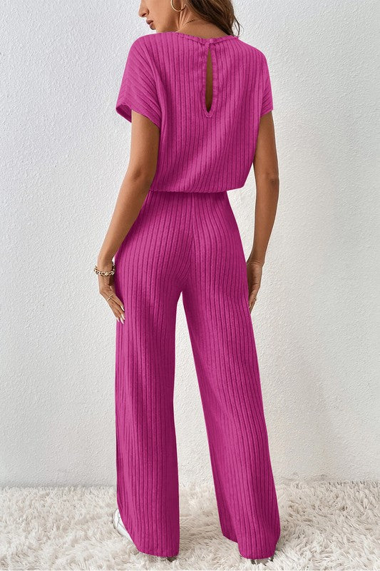 a woman wearing a pink jumpsuit with a back cutout