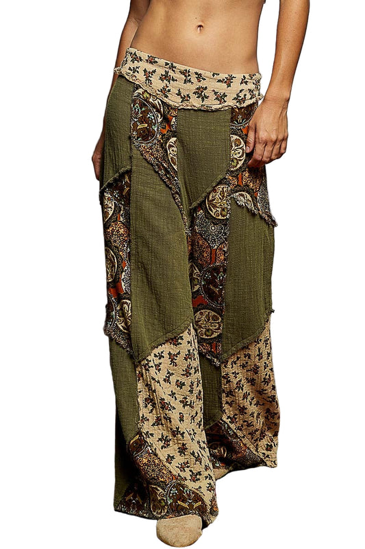 Person wearing a pair of green and patterned wide-leg pants on a colorful rug.