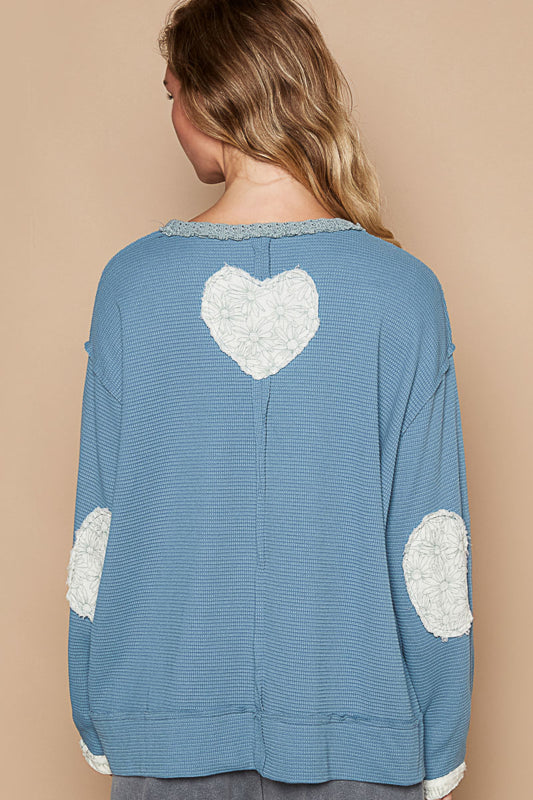 a woman wearing a blue sweater with a white heart on it
