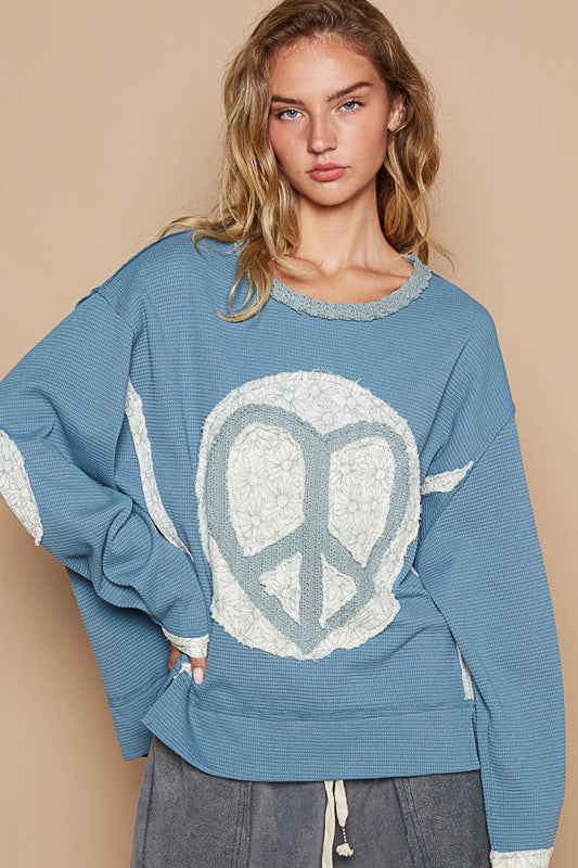 a woman in a blue sweater with a peace sign on it