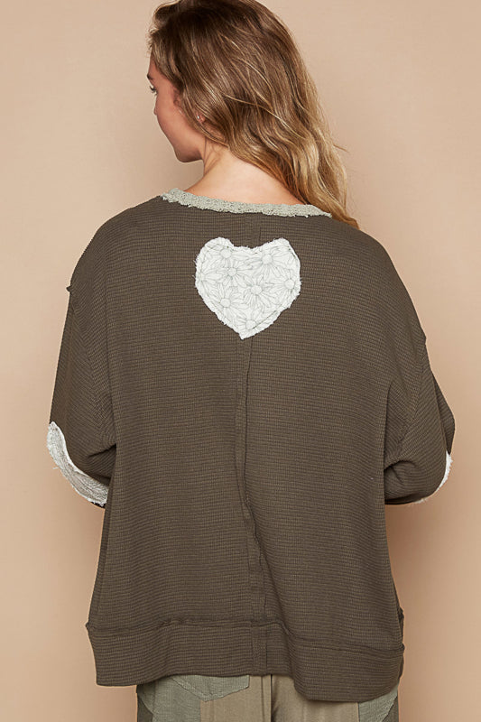 a woman wearing a brown sweater with a white heart on it