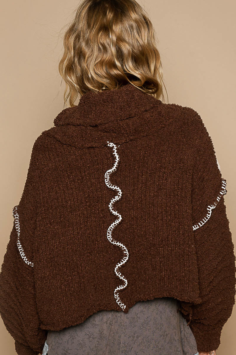 a woman wearing a brown sweater with a spiral design on it