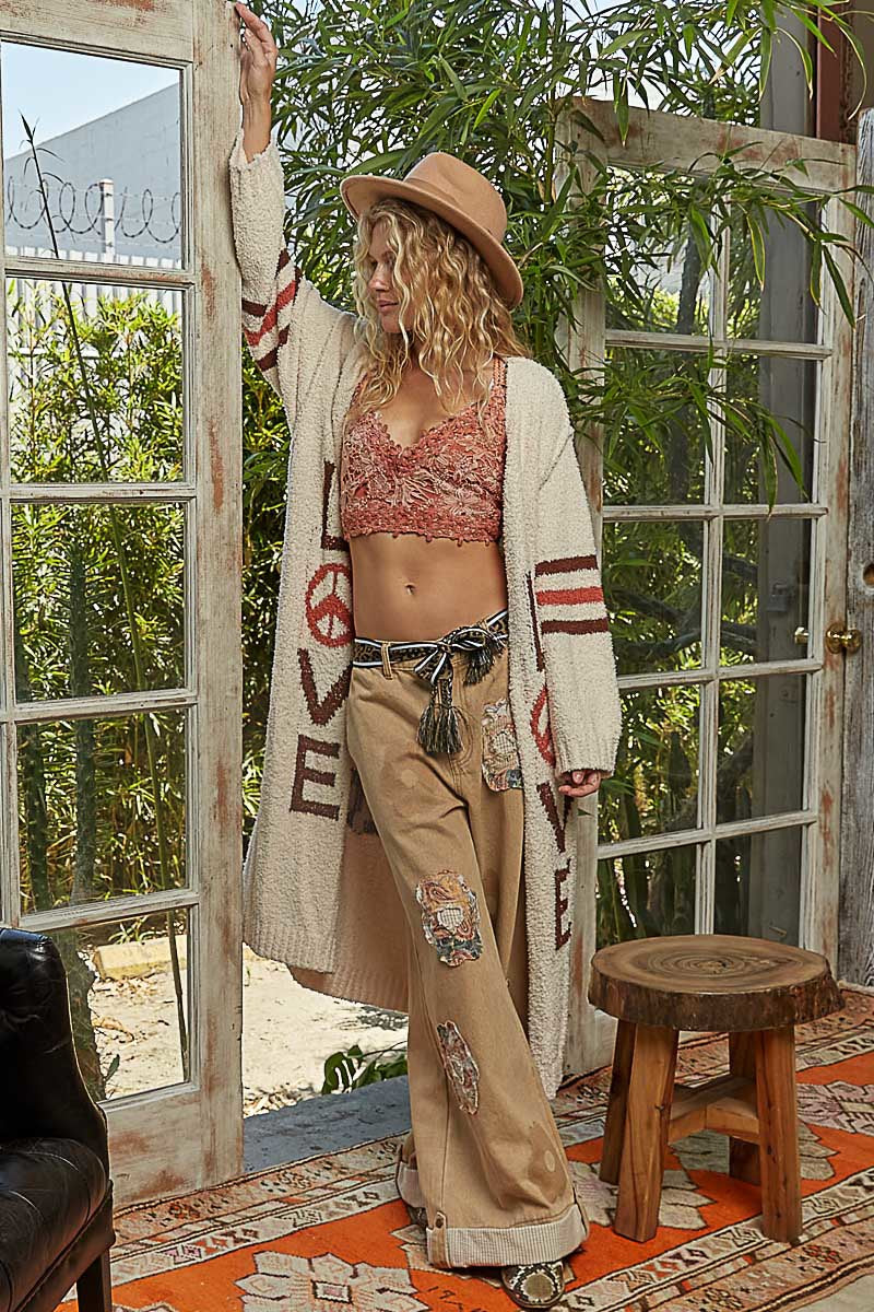 Woman in a bohemian outfit standing in a room with large windows and plants.