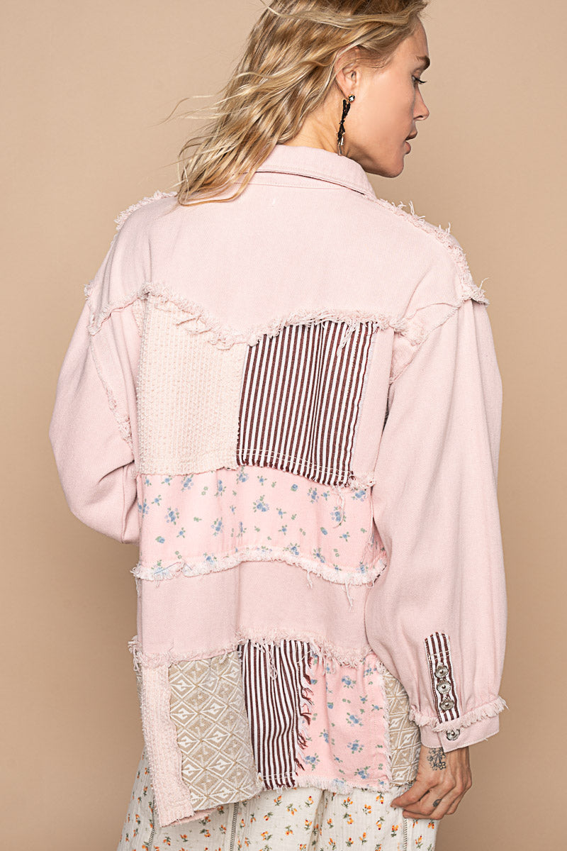 a woman wearing a pink jacket with patches on it