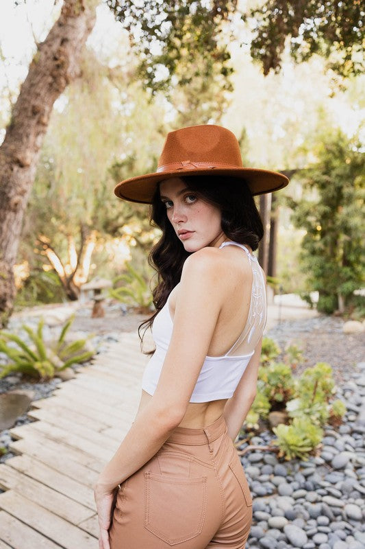 a woman wearing a brown hat and tan pants