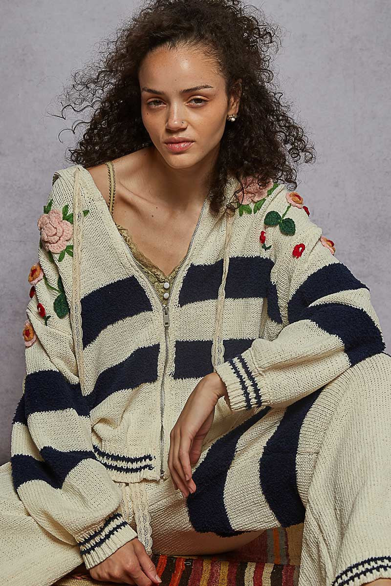 Woman wearing a striped cardigan with floral and fruit patterns on a gray background