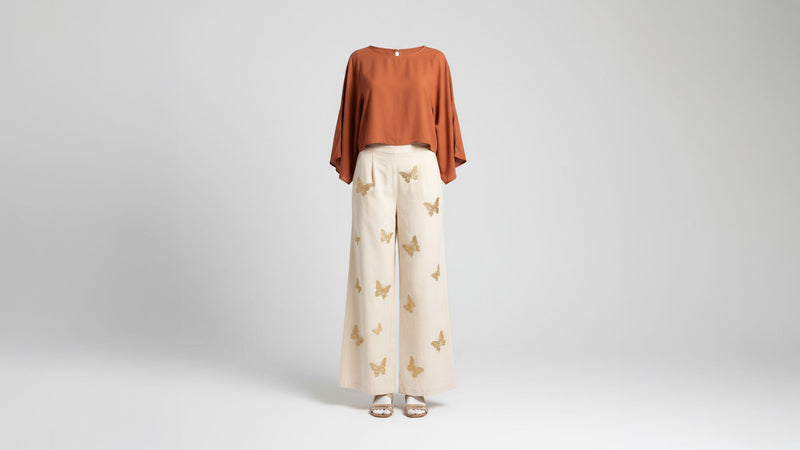 Women's wide-leg boho trousers with butterfly embroidery styled with terracotta blouse, ghost mannequin studio shot - BellanBlue