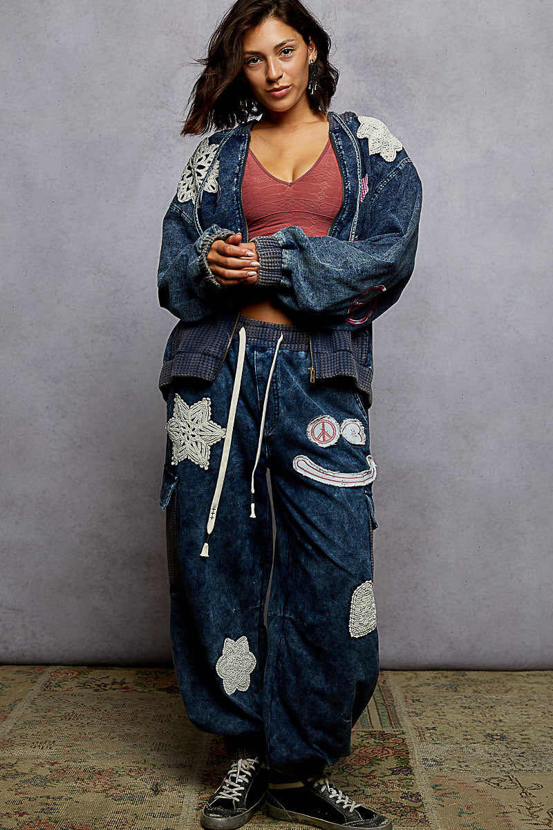 Person wearing a blue embroidered jacket and pants against a gray background