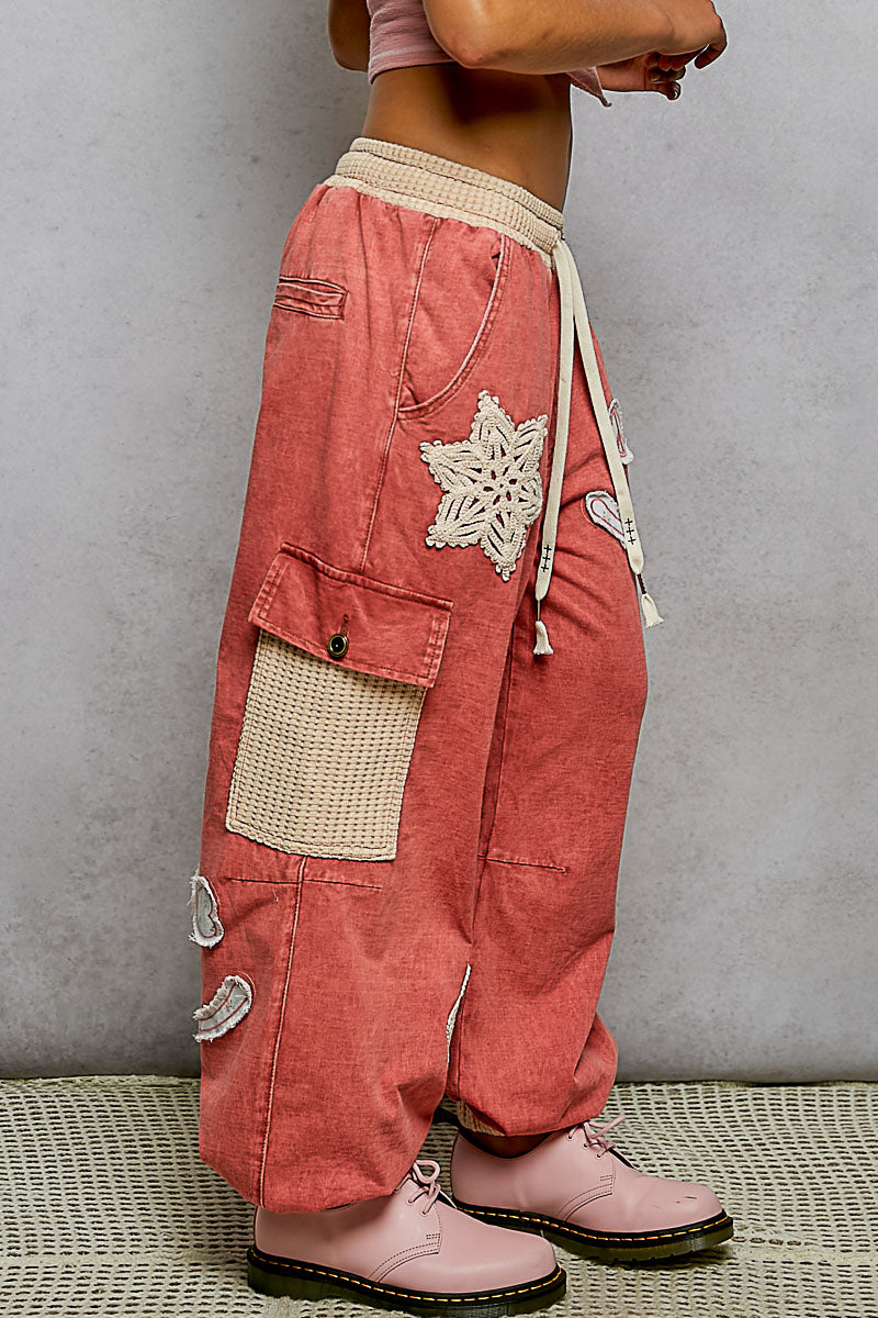 Person wearing pink cargo pants with decorative elements on a neutral background