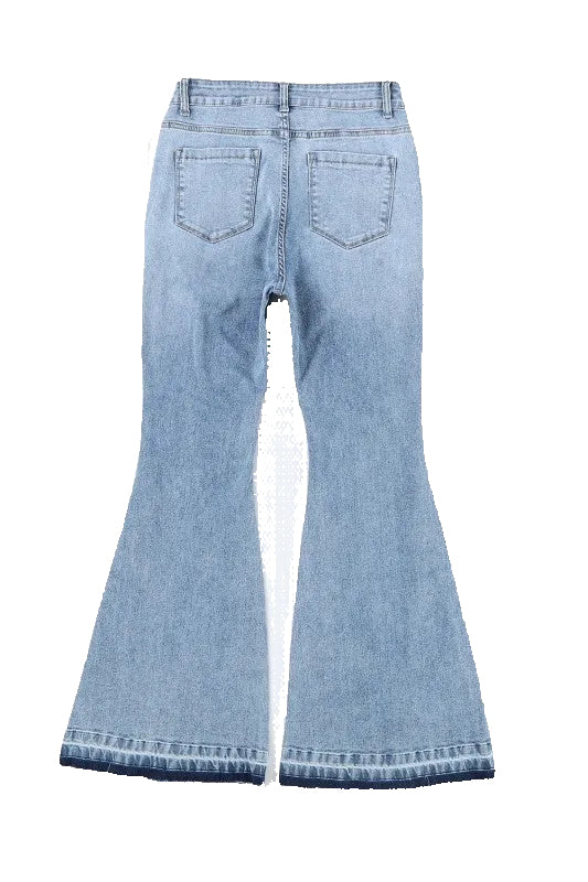 Light blue flared jeans on a white surface with sunglasses and a book in the background.