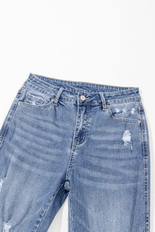 Blue denim jeans with slight distressing on a white background