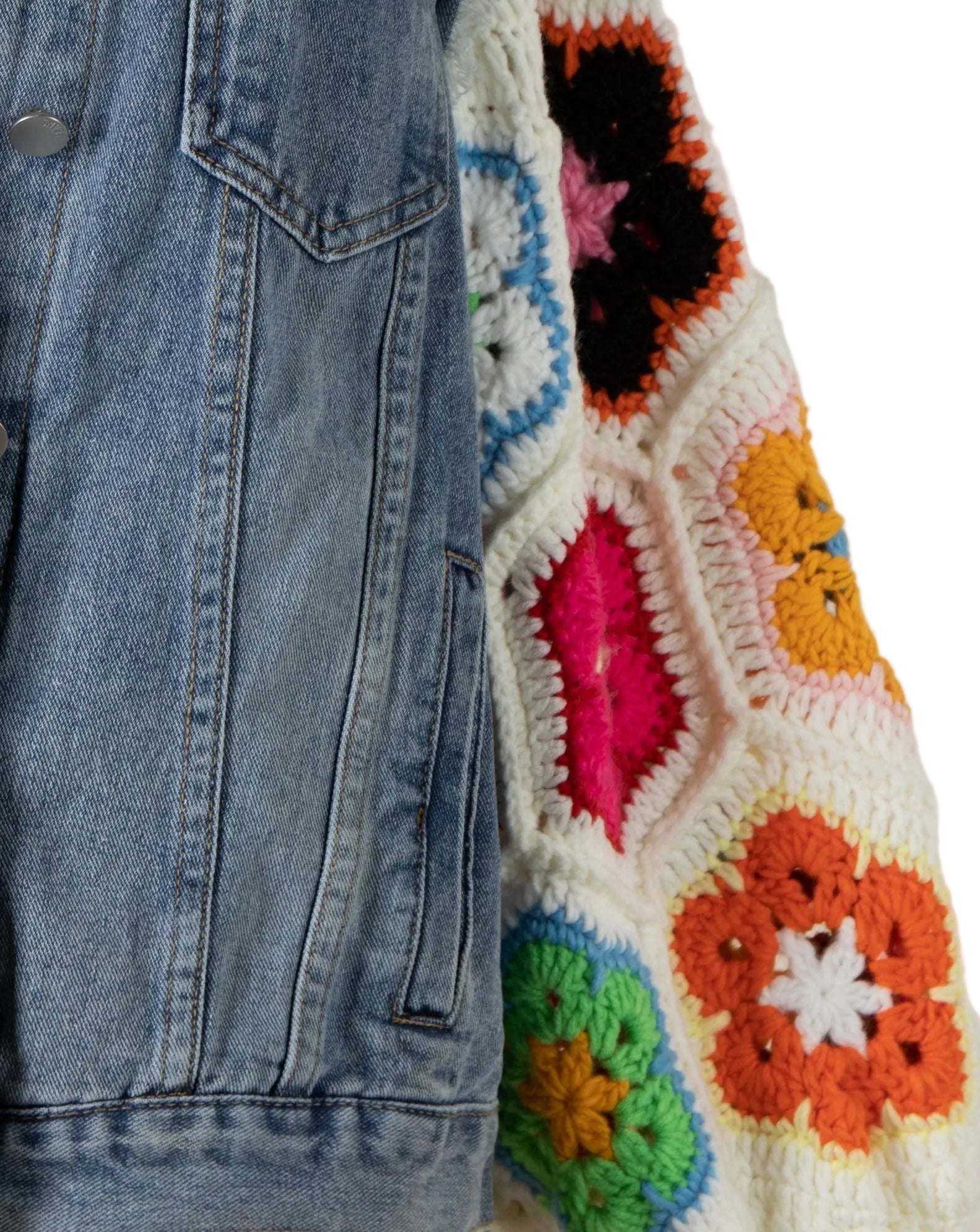 Close-up of a denim jacket next to a colorful crocheted blanket with hexagonal patterns.