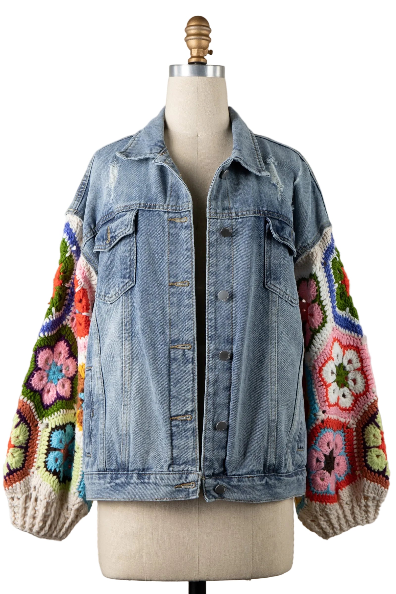Women's light blue wash denim trucker jacket front view with colorful granny square crochet balloon sleeves and cream borders