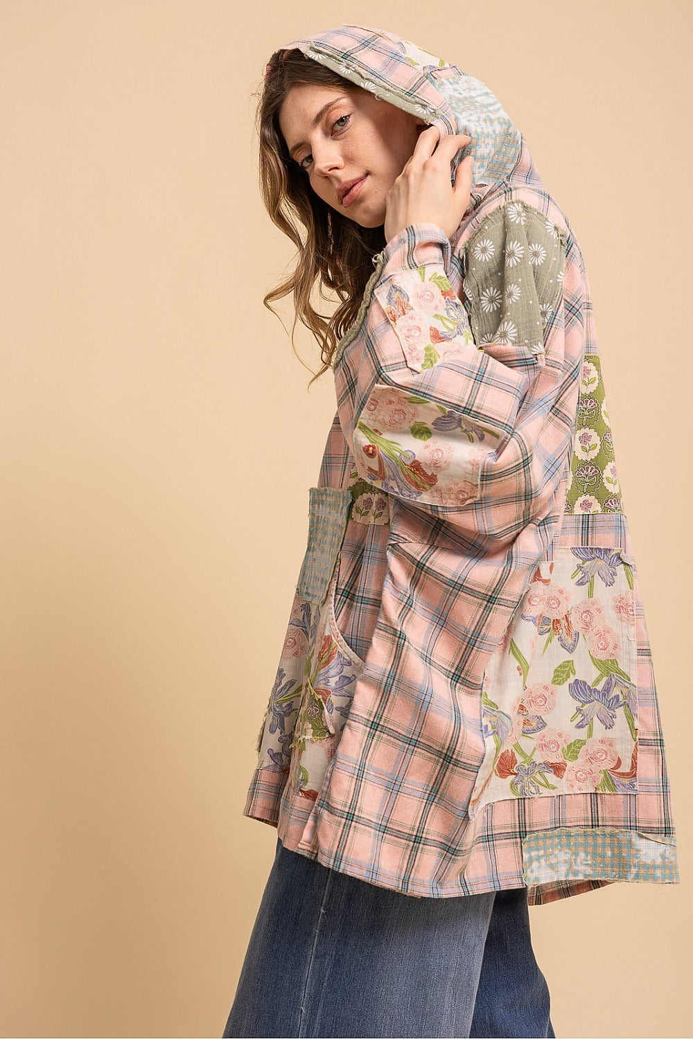 Woman wearing a floral and plaid patterned coat on a beige background