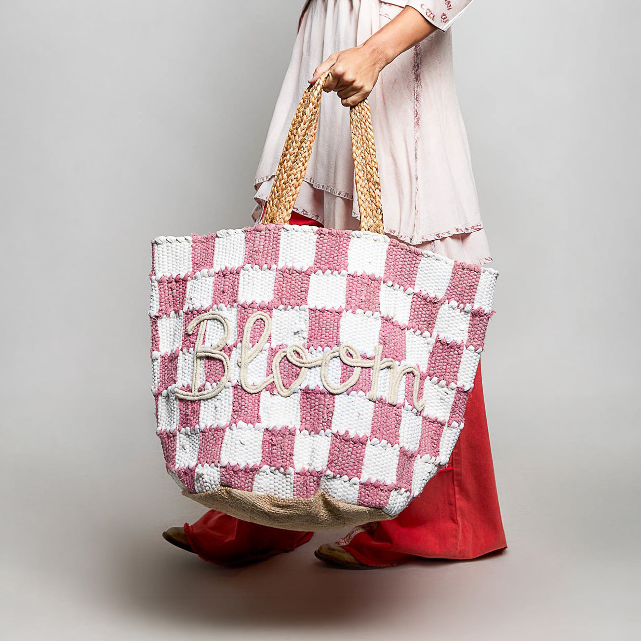POL Clothing Pink BLOOM handwoven tote bag carried at hip, front view showing checkerboard pattern and braided handles
