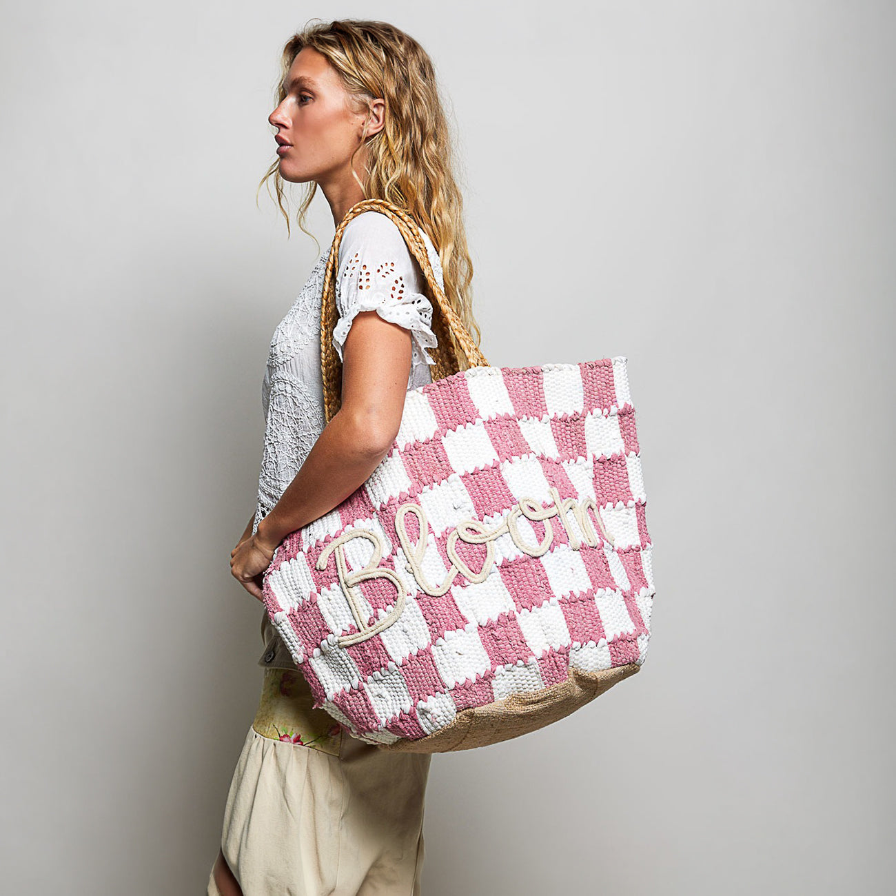 POL Clothing Pink BLOOM handwoven tote bag on model, side profile view showing checkerboard texture and rope lettering detail
