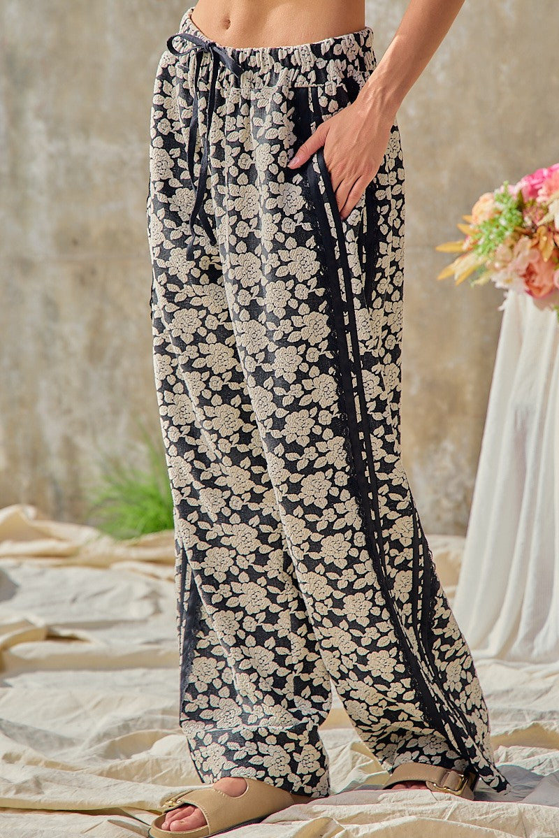 BiBi women's black floral wide leg pants, elastic drawstring waistband detail, side pocket view on model
