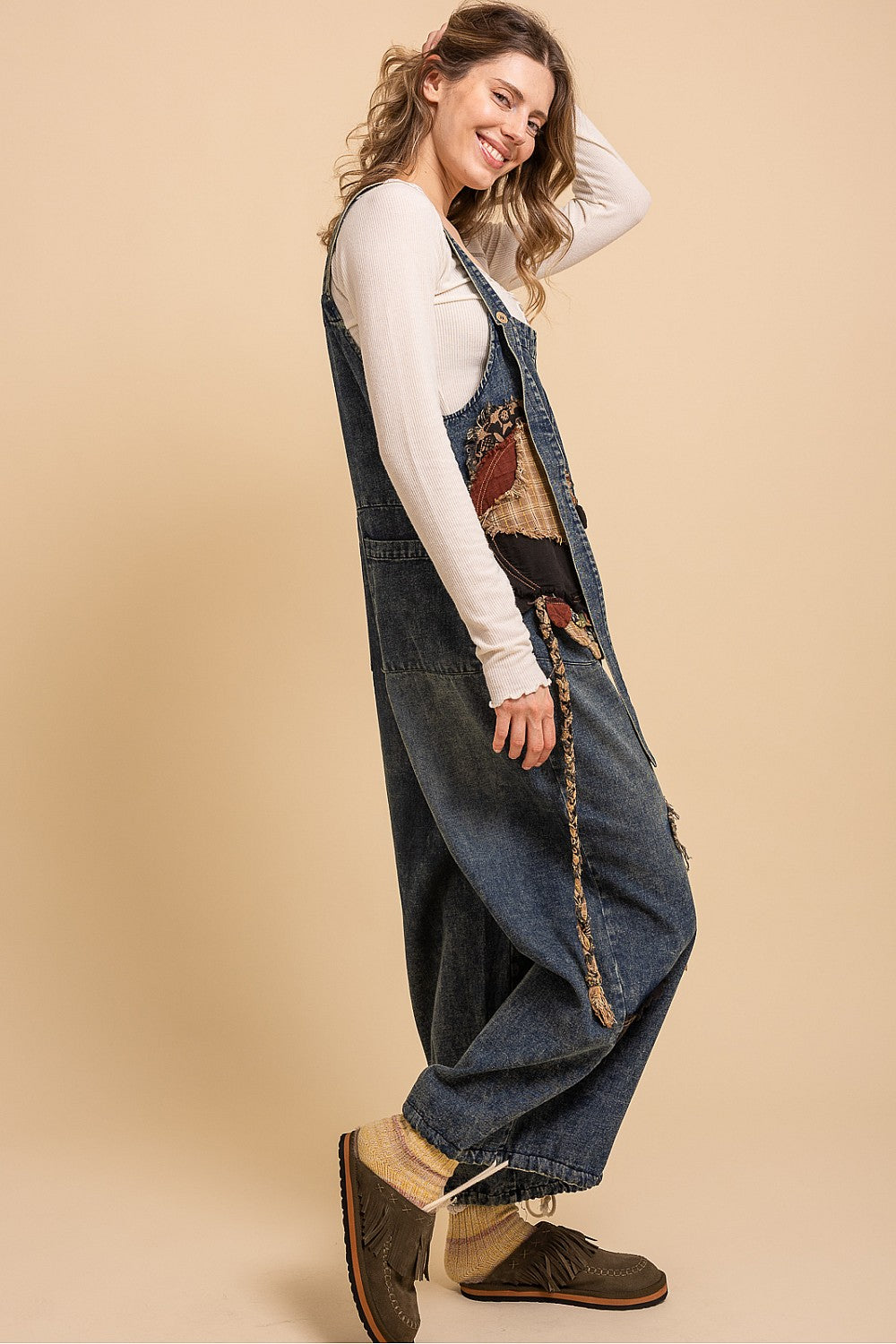 Bluevelvet denim patchwork overalls on model, angled view showing fringe-edge patchwork panels and wide-leg drape
