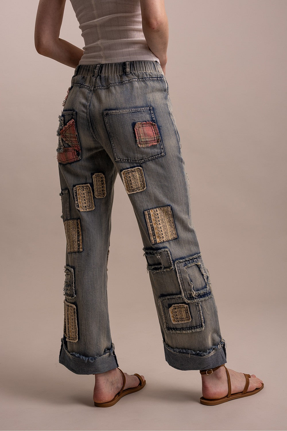 Blue Velvet wide-leg denim pants, back view on model showing colorful patchwork panels and frayed cuffed hem detail
