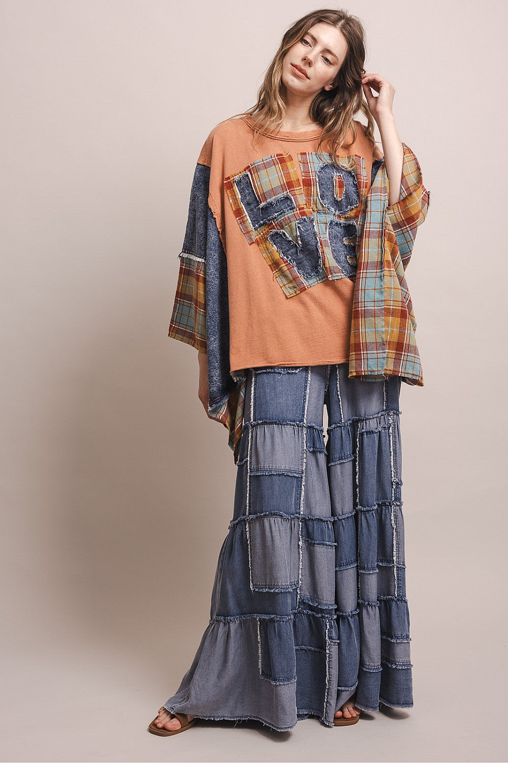 Bluevelvet coral patchwork poncho top, movement shot showing wide plaid sleeve drape and raw frayed hem detail
