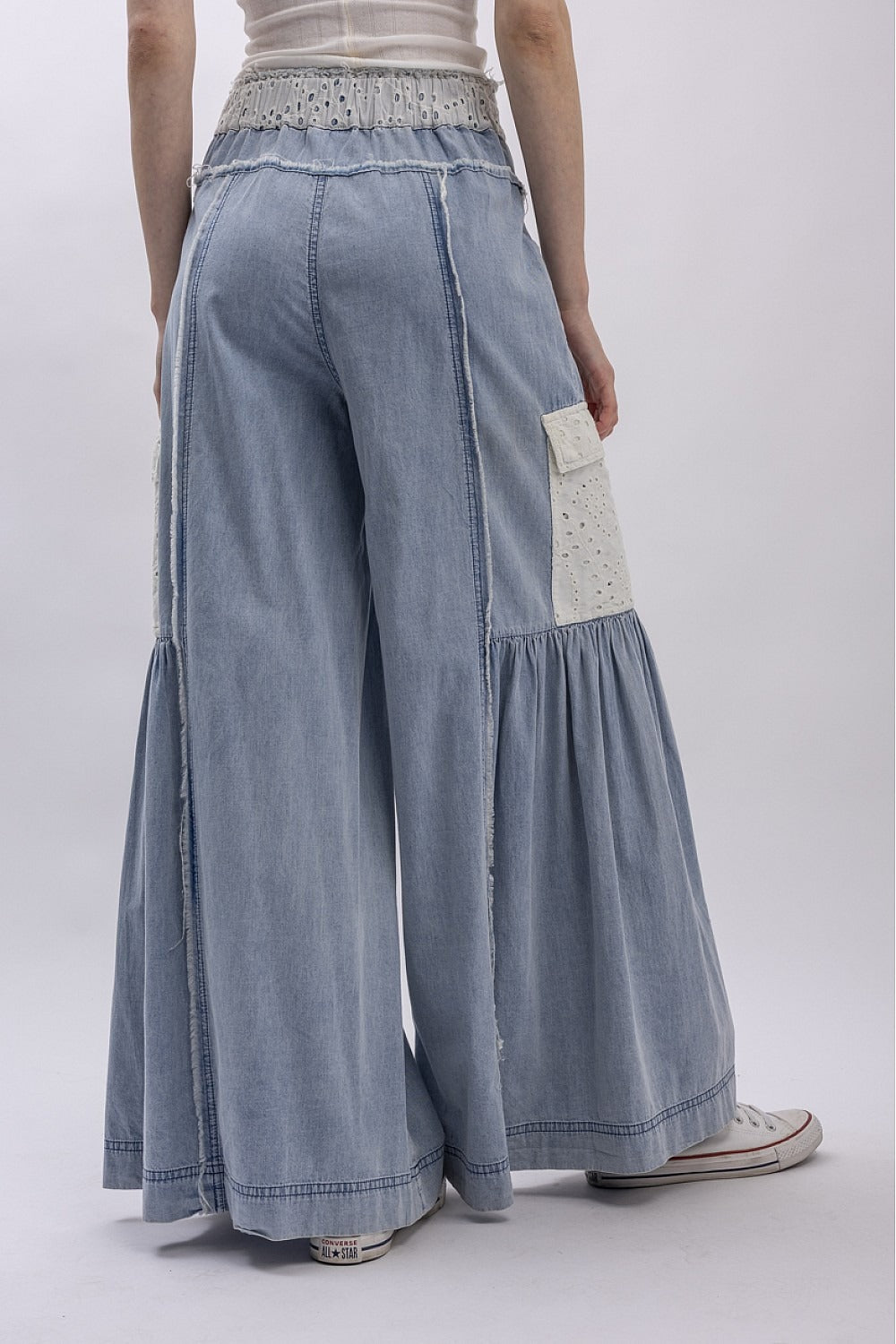 Light blue denim wide-leg pants with decorative elements on a white background