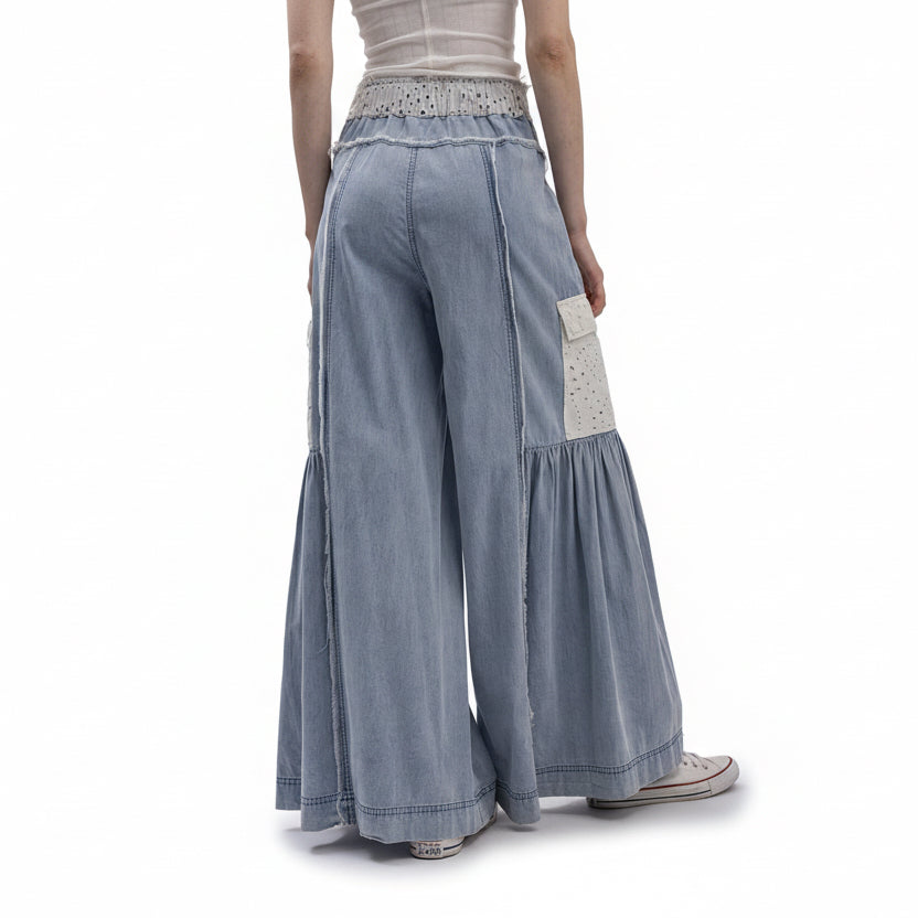 Light blue denim wide-leg pants with decorative elements on a white background