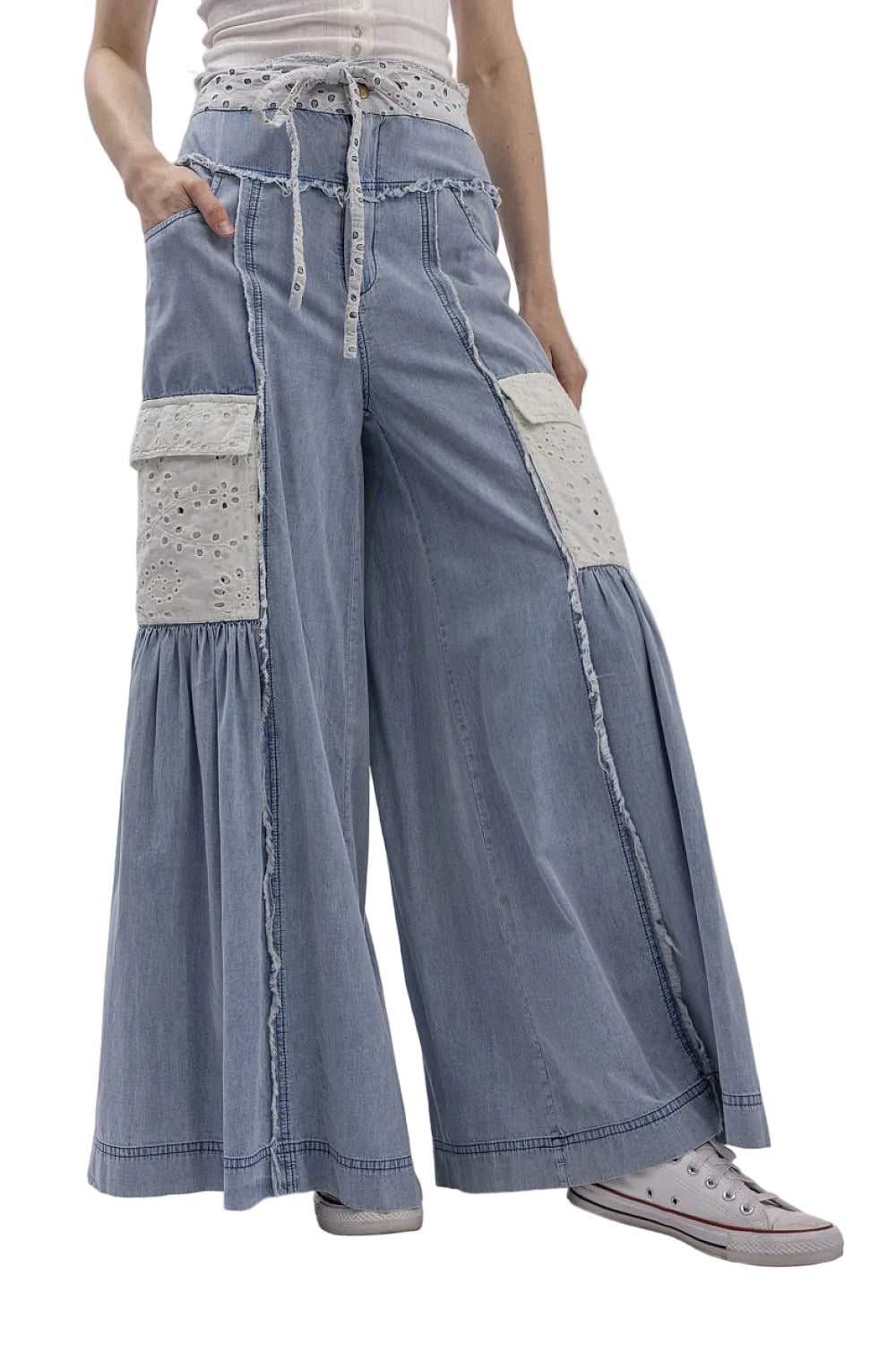 Person wearing blue denim pants with white lace details on a plain background