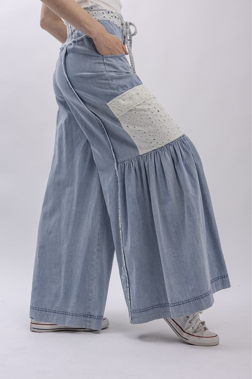 Light blue denim pants with a white patch on a white background