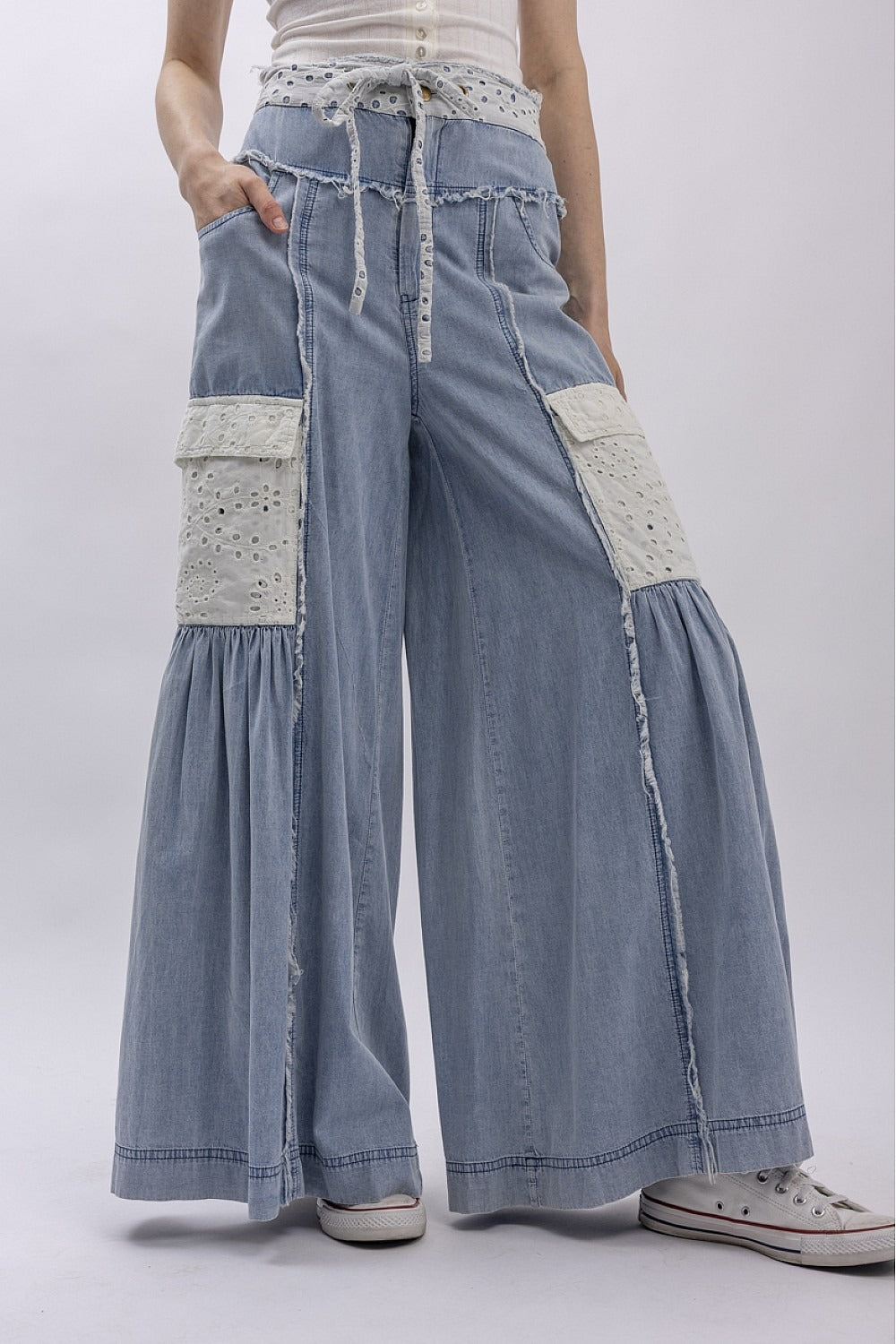 Denim pants with white patches worn by a person on a white background