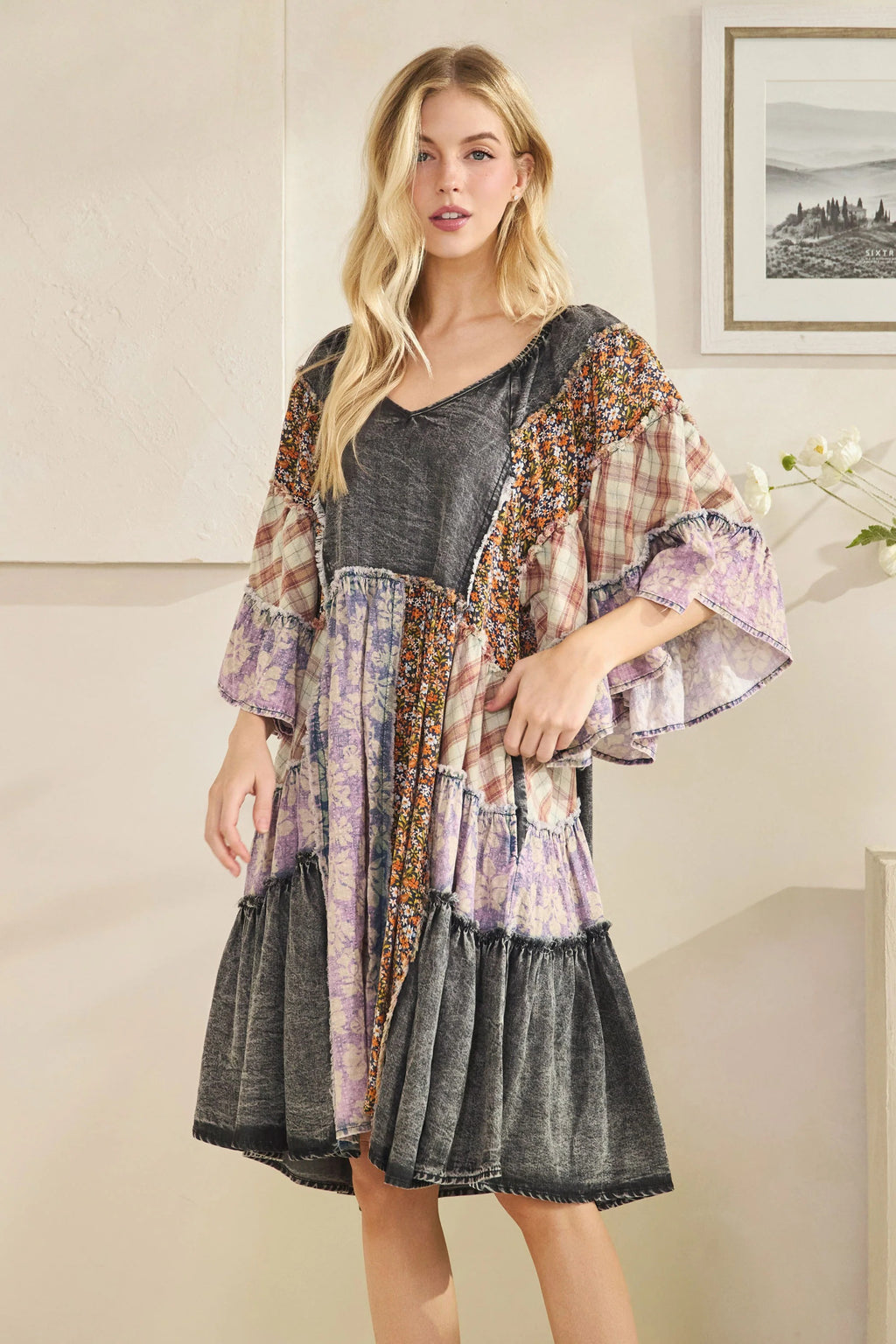 Woman wearing a layered dress with a floral kimono over a gray top in a room.
