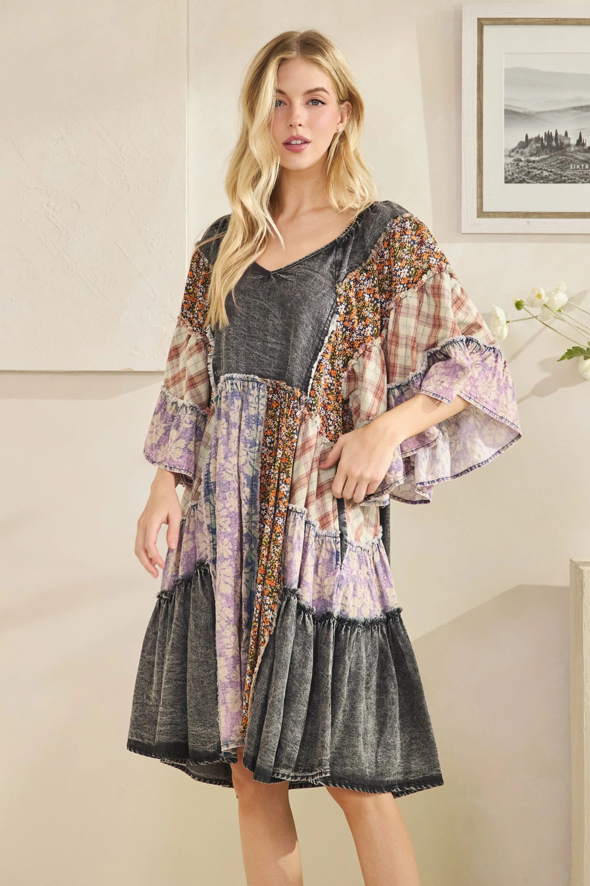 Woman wearing a layered dress with a floral kimono over a gray top in a room.