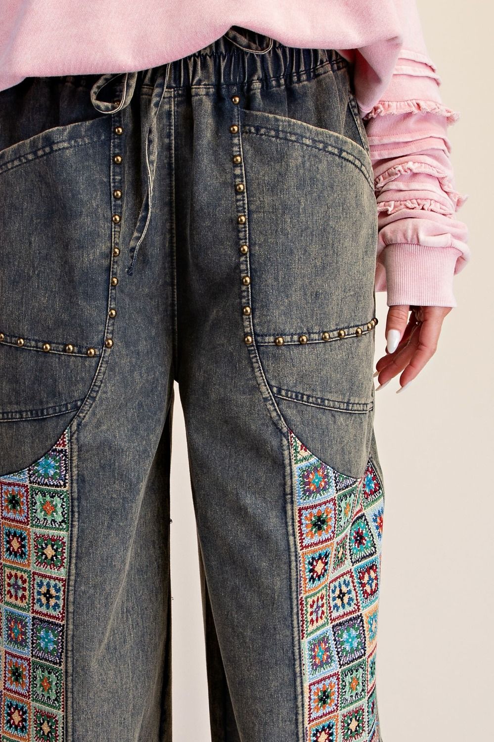 Easel Clothing dirty denim wide-leg jogger pants, three-quarter front view with crochet patchwork panels on model
