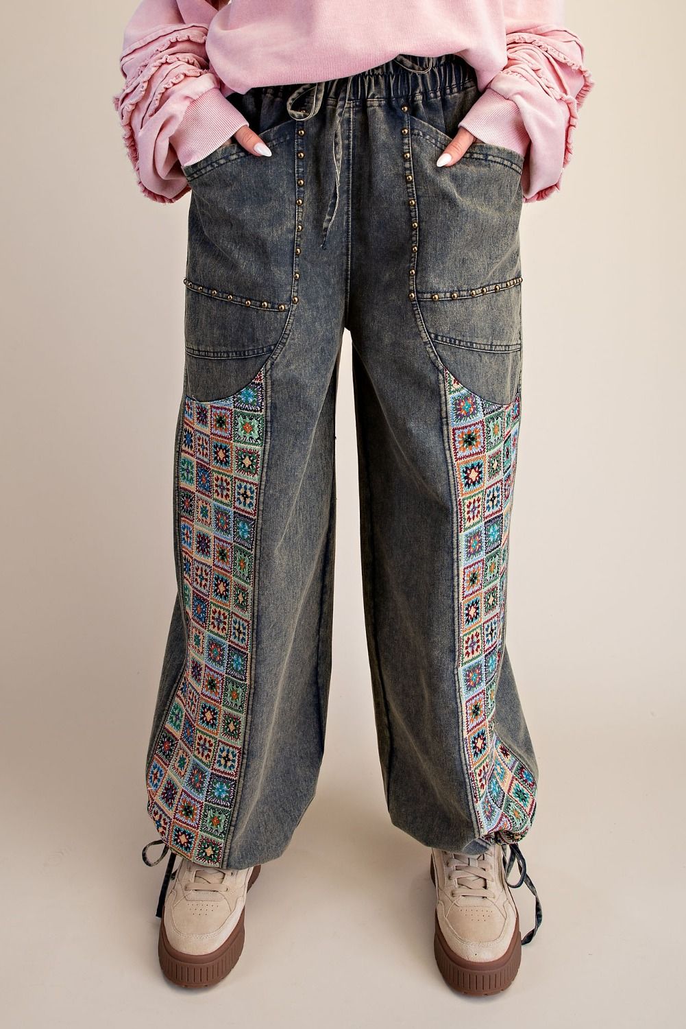 Easel Clothing dirty denim wide-leg pants close-up showing colorful crochet jacquard patchwork side panel
