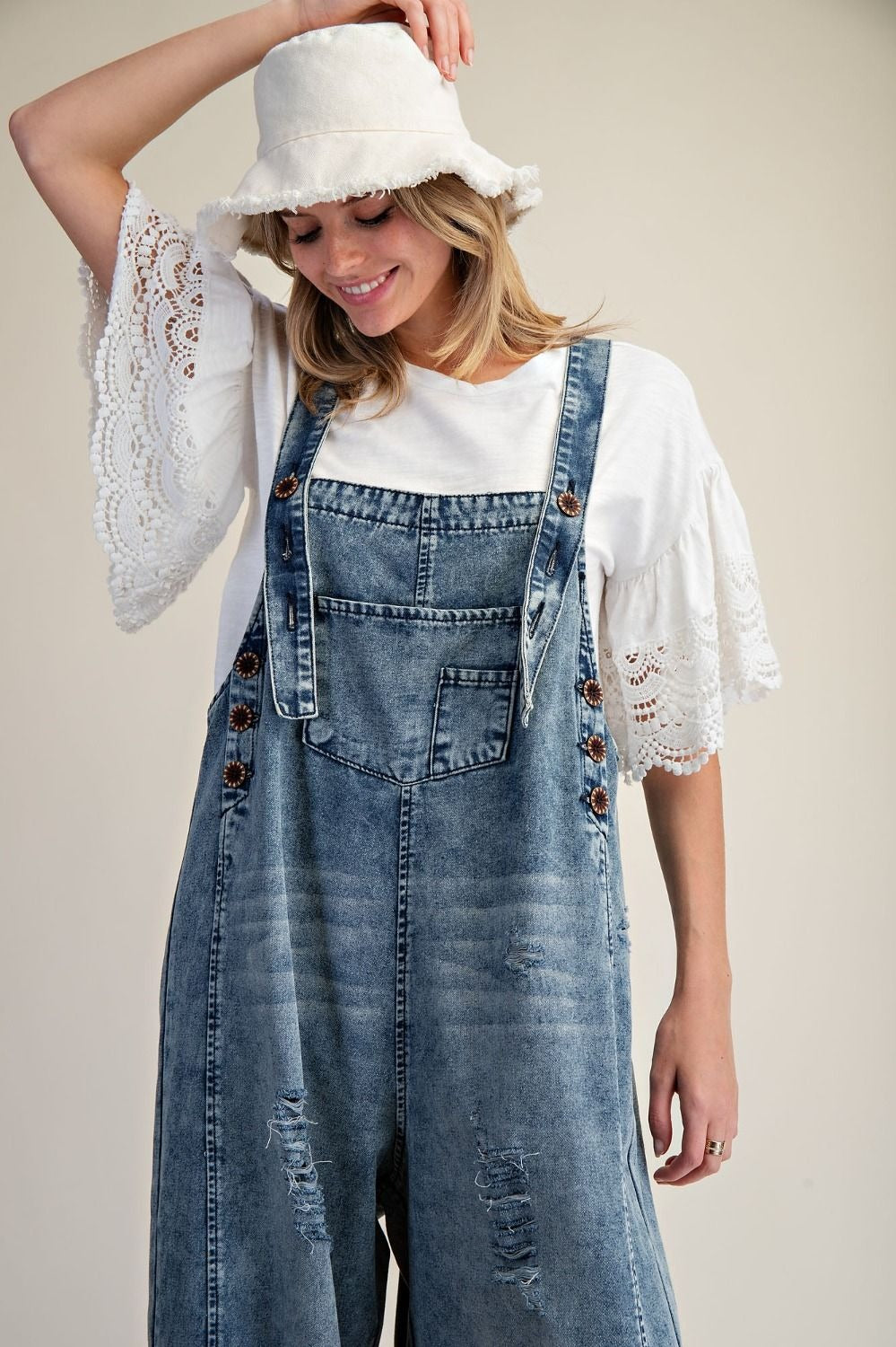 Easel Clothing women's distressed denim overalls from the side, showing loose wide legs