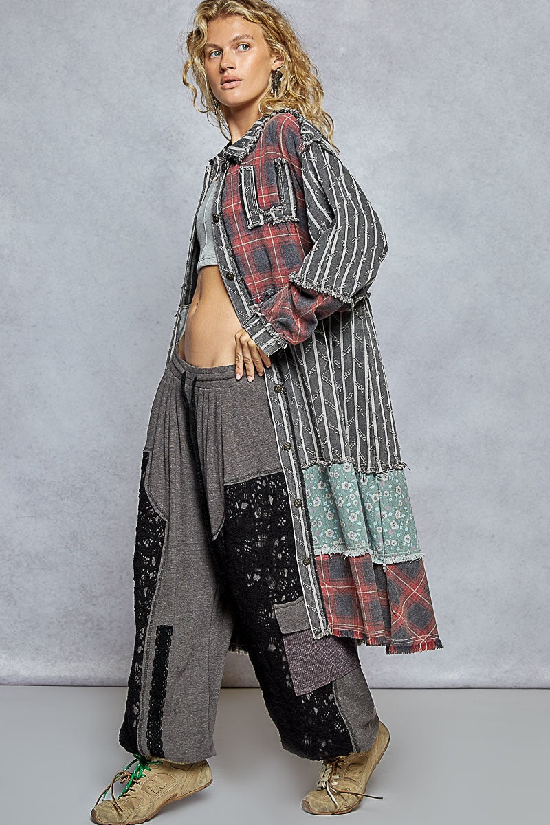 Person wearing a long, patchwork-style garment with a plaid pattern against a gray background