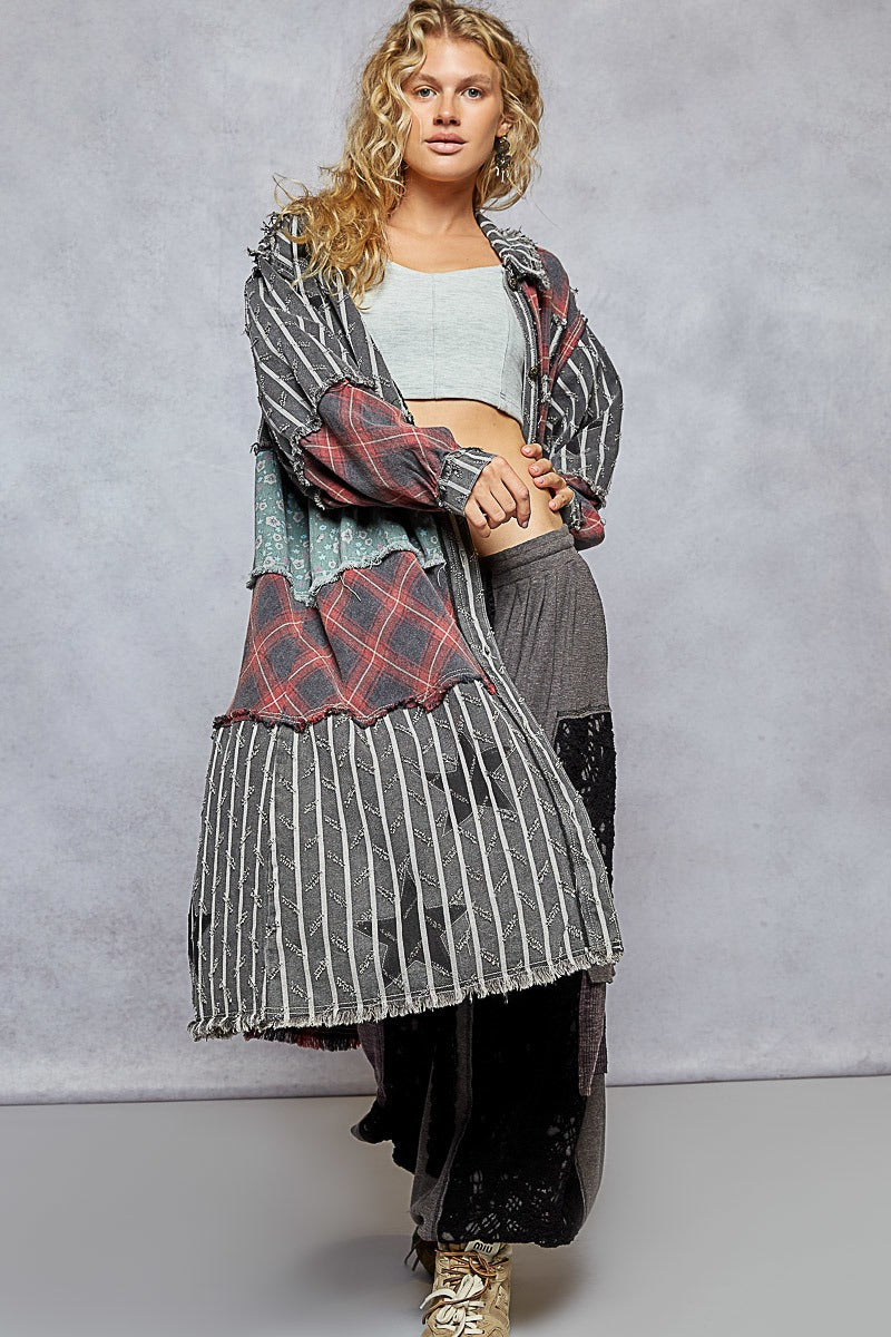 Woman wearing a layered outfit with a plaid jacket and striped skirt against a plain background