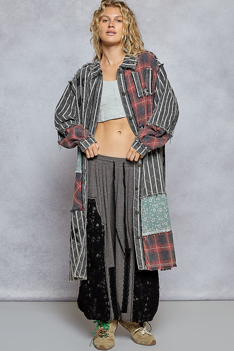 Person wearing a long, patterned coat over a casual outfit with a plain background