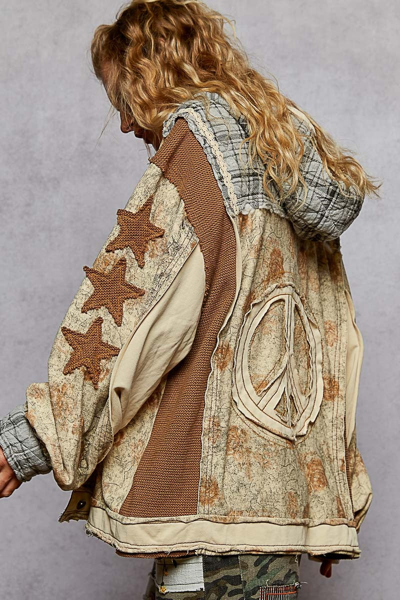 Person wearing a unique, patterned jacket with stars and a peace symbol on a plain background
