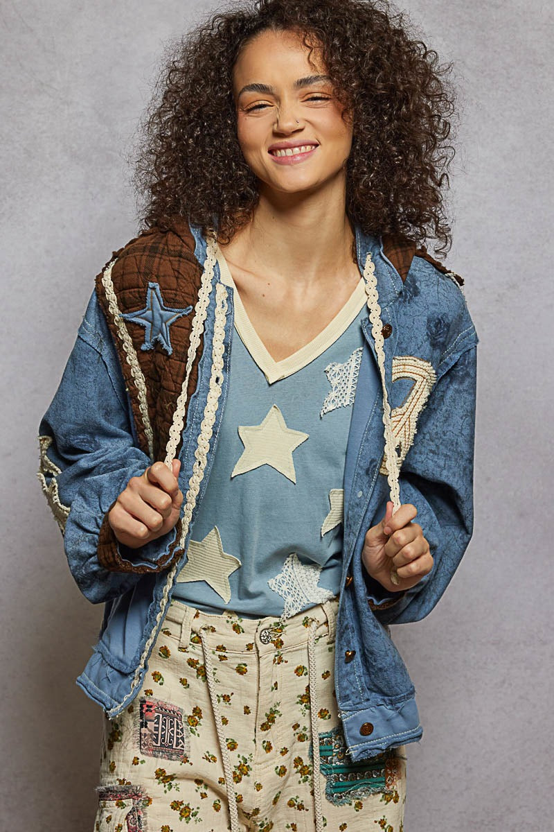 Person wearing a denim jacket with star patterns and floral pants against a gray background