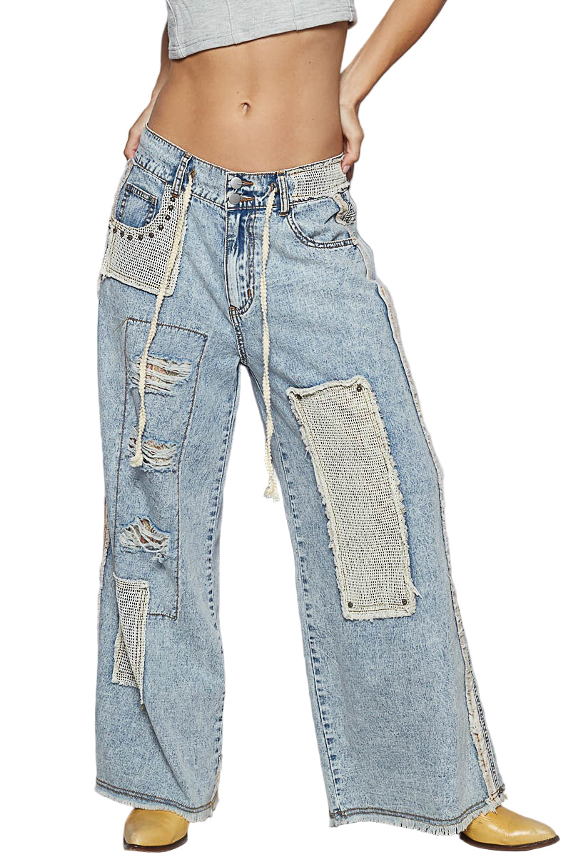 Person wearing patchwork jeans with a plain background