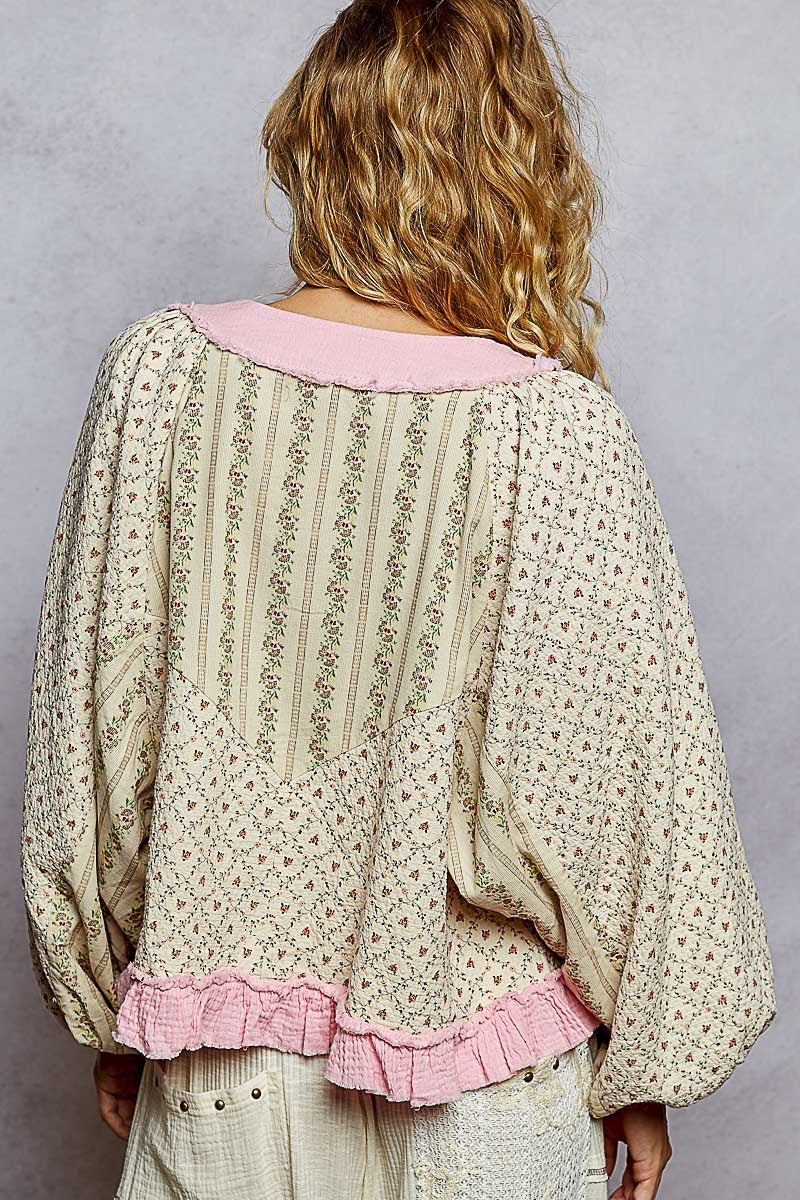 Person wearing a floral blouse with pink trim on a plain background