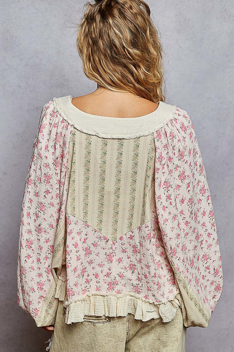 Back view of a person wearing a floral blouse with a plain background